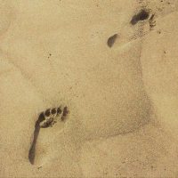 twee voetstappen in zand als metafoor voor eigen kracht